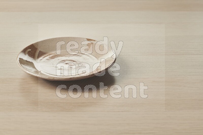 A multicolored pottery plate on light wooden background