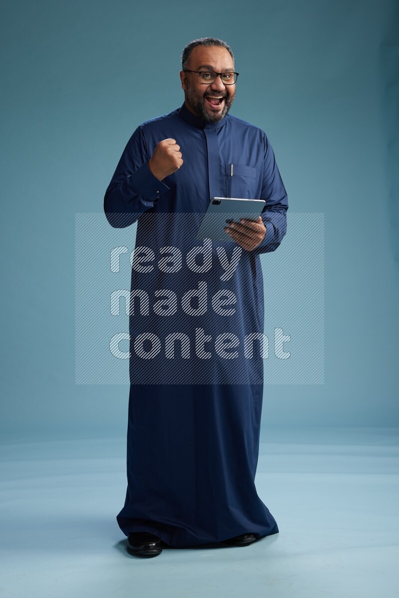 Saudi Man without shimag Standing working on tablet on blue background