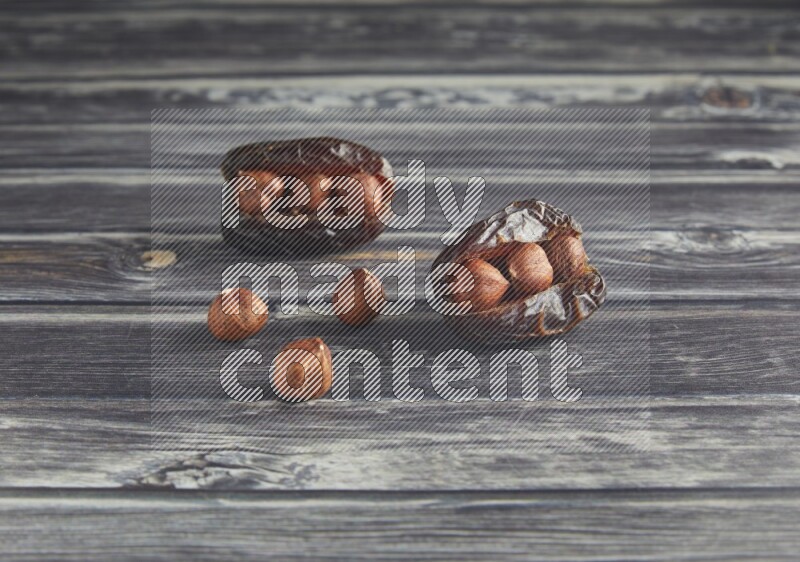 two hazelnut stuffed madjoul dates on a wooden grey background