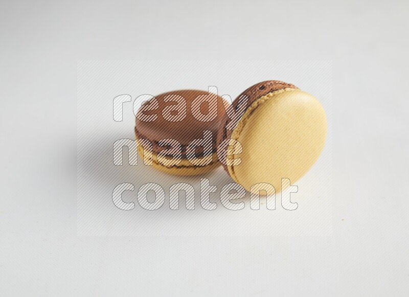 45º Shot of two Yellow and Brown Chai Latte macarons on white background