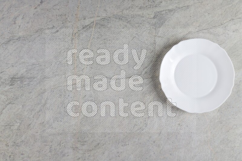 A white ceramic circular plate on grey marble background