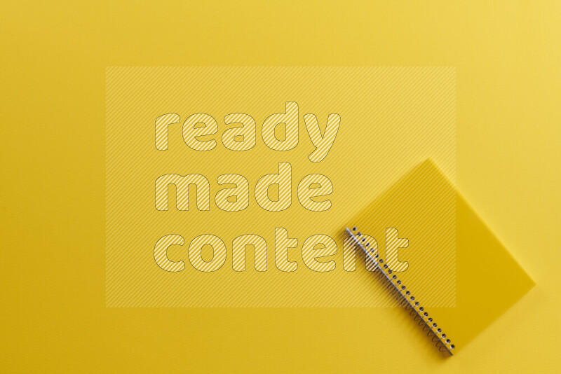 A yellow notebook with different school supplies on yellow background