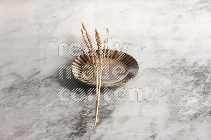 Wheat stalks on multicolored pottery plate on grey marble background