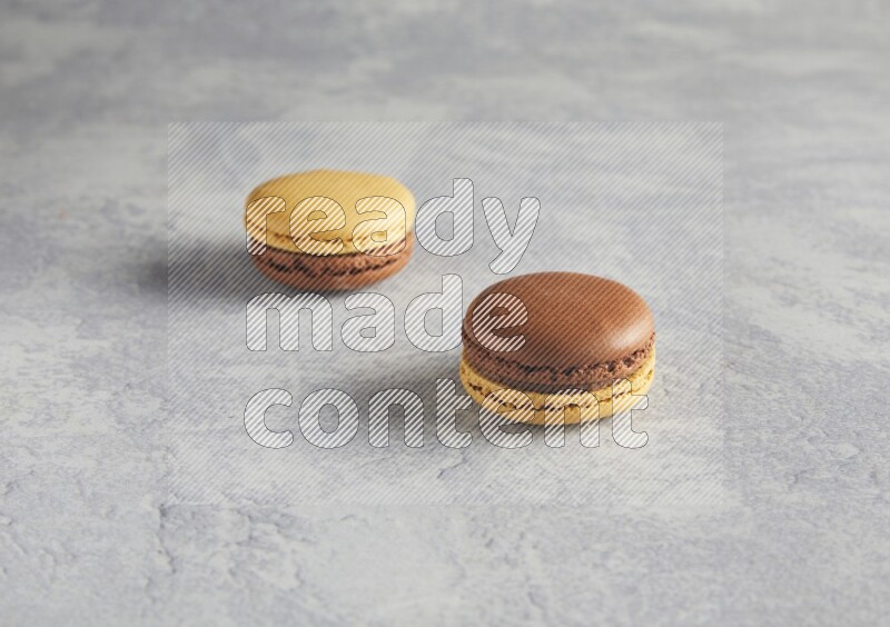 45º Shot of two Yellow and Brown Chai Latte macarons r on white  marble background