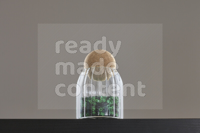 Sequins in a glass jar on black background