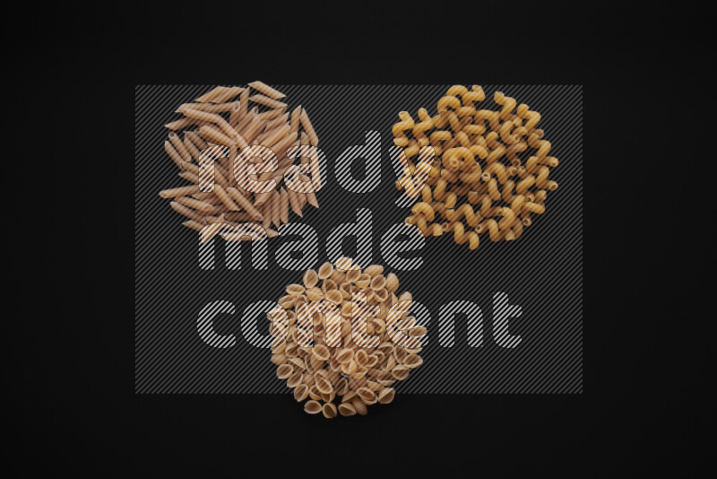 Different pasta types in bunches on black background
