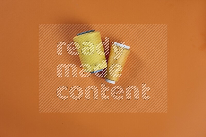 مجموعة من أدوات الخياطة والتفصيل صفراء اللون على خلفية برتقالية