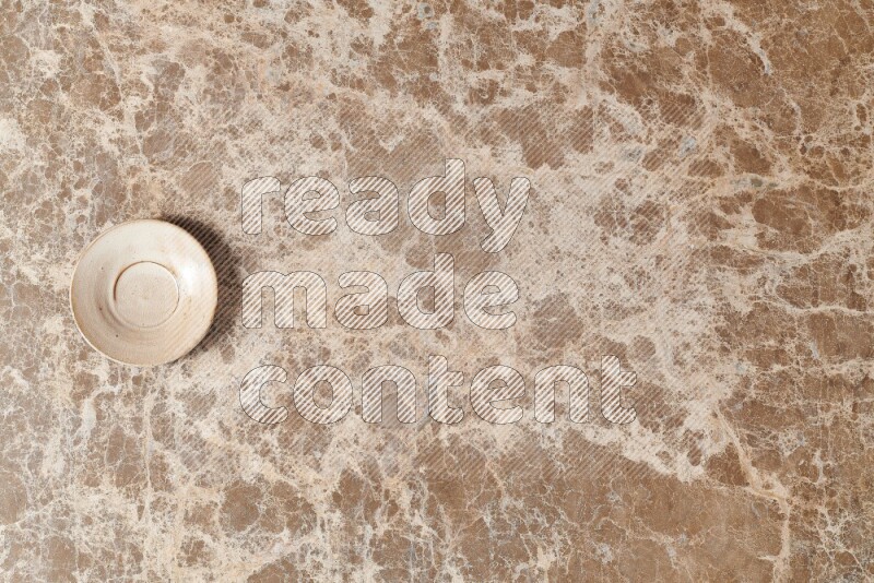 A beige pottery plate on beige marble background