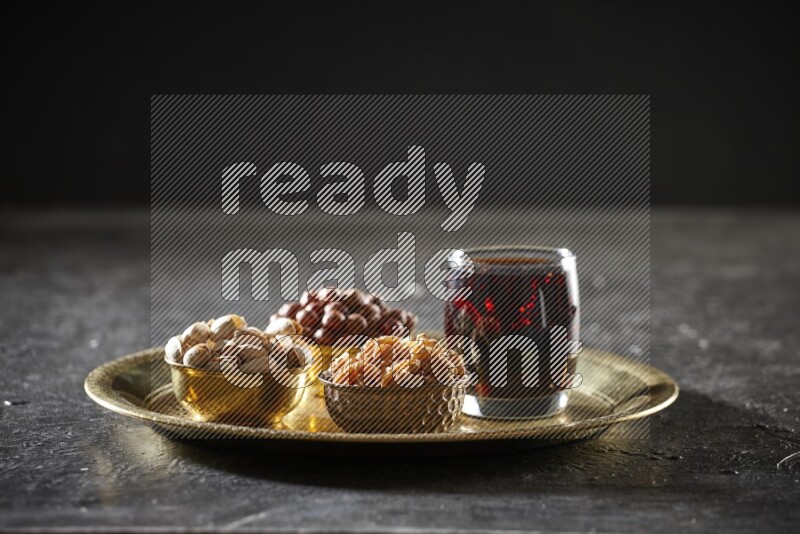 Nuts in metal bowls with tamarind on a tray in dark setup