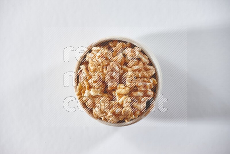 A beige ceramic bowl full of peeled walnuts on a white background in different angles