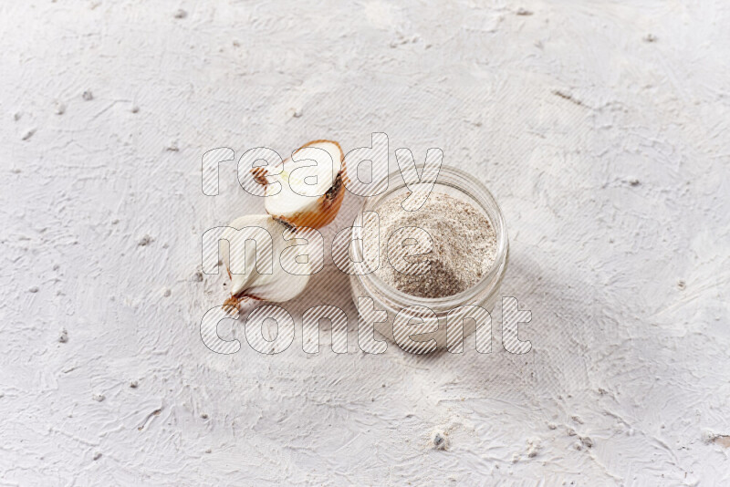 A glass jar full of onion powder on white background