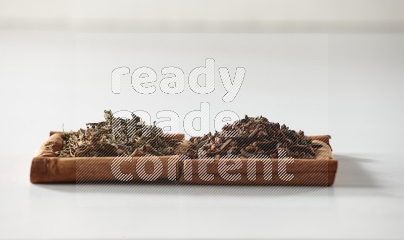 2 squares of cinnamon sticks full of cloves and dried basil on white flooring