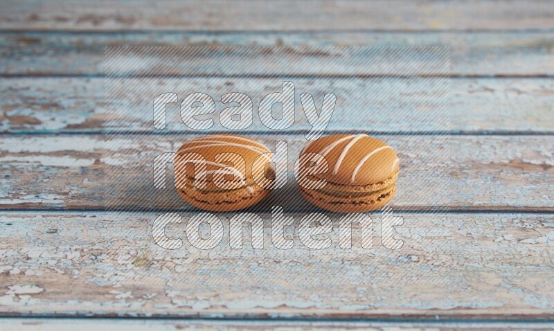 45º Shot of two Brown Irish Cream macarons on a  light blue wooden background