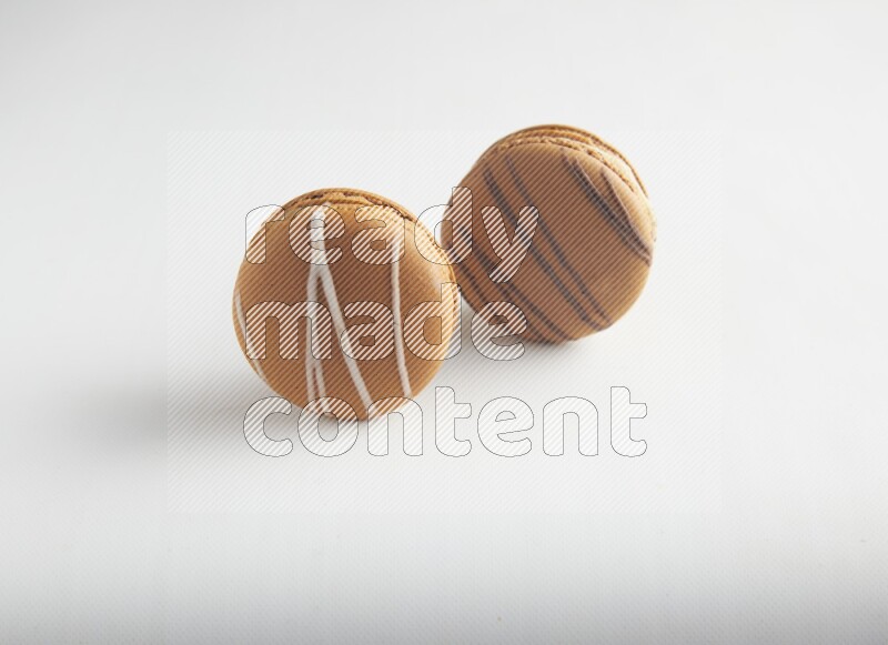 45º Shot of of two assorted Brown Irish Cream, and light brown  Almond Cream macarons on white background