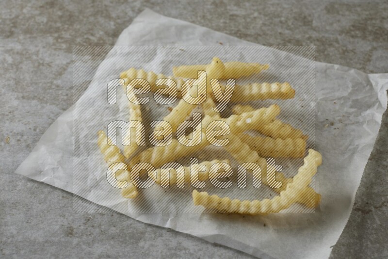 crinkle fries on parchment paper on grey textured counter top