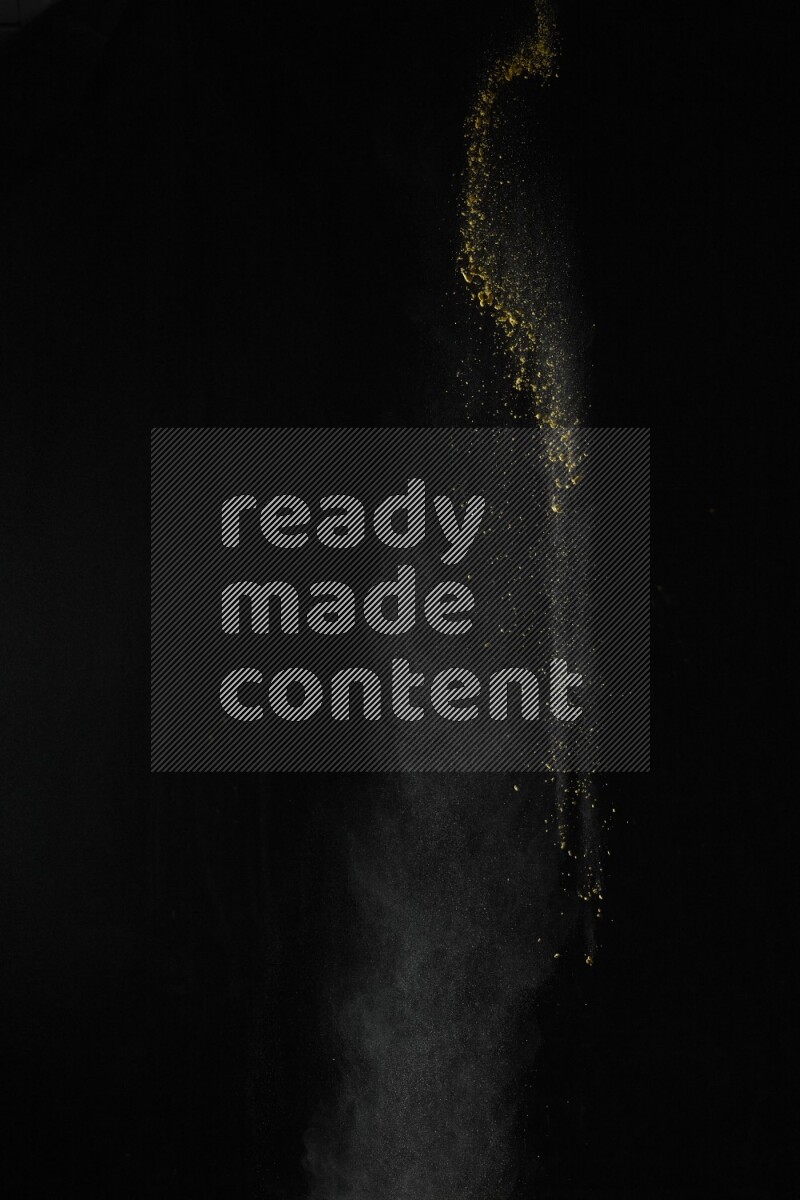 A side view of yellow powder explosion on black background