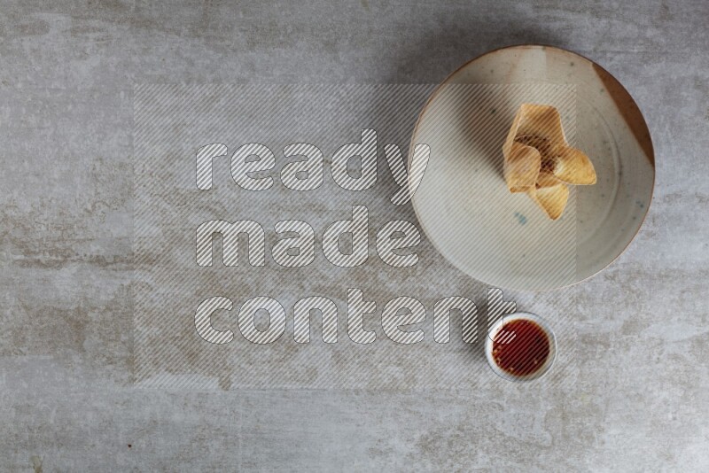 wonton cups with soy sauce ramkin on multi colored pottery on grey textured counter top