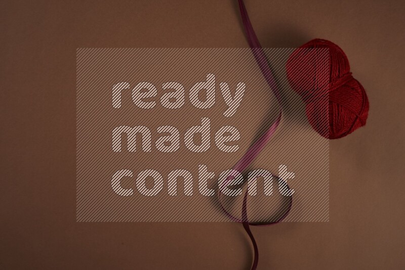 A red collection of sewing and tailoring tools arranged on a brown background