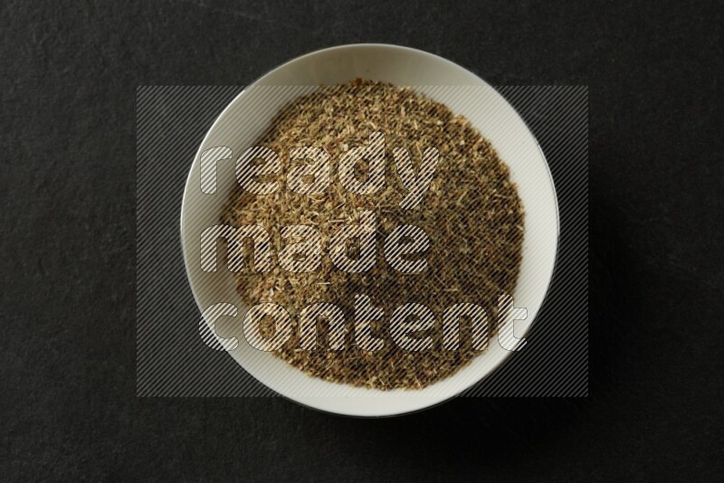 white ceramic round sauce dish filled with herbs on grey textured countertop