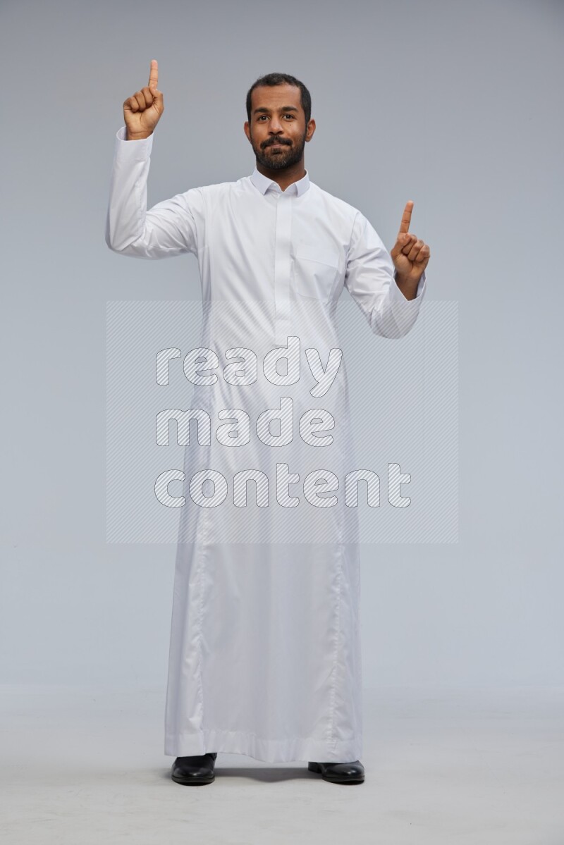 Saudi man Wearing Thob standing interacting with the camera on Gray background