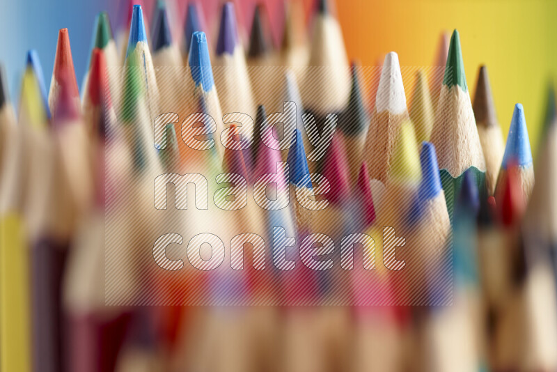 The image captures a close-up of sharpened colored pencils on multicolored background