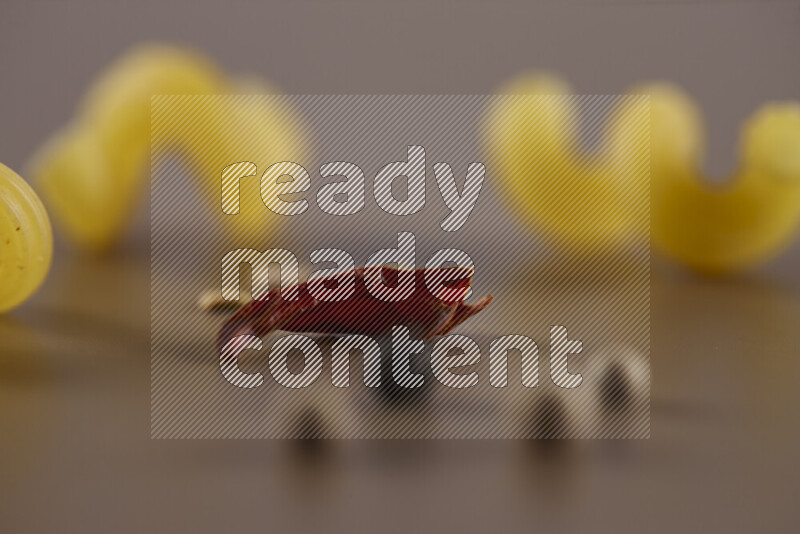 معكرونة مع مكونات متنوعة من الطماطم والثوم والبصل والفلفل الأحمر والفلفل الأسود والفلفل الأبيض وأوراق الغار وإكليل الجبل والهيل على خلفية بيج