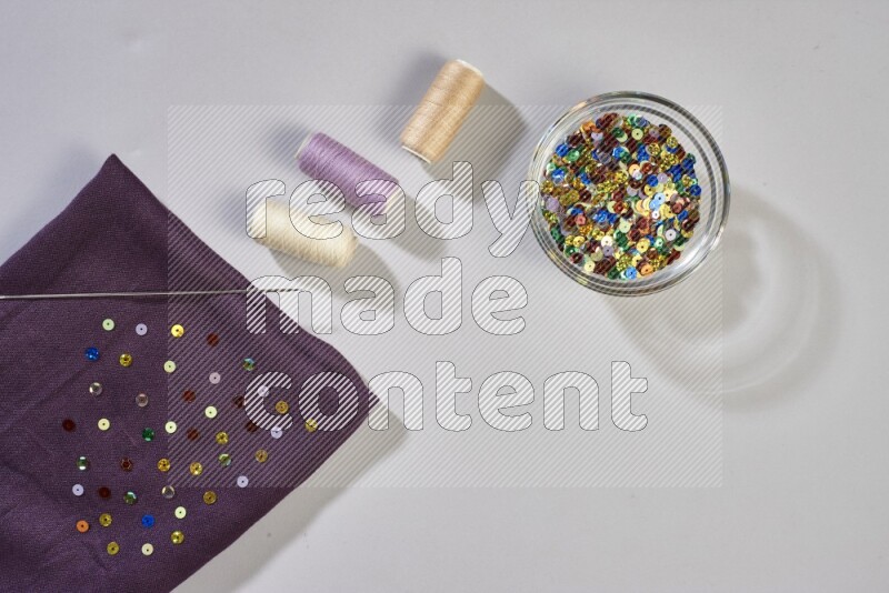 Multicolored fabrics with sewing supplies on grey background