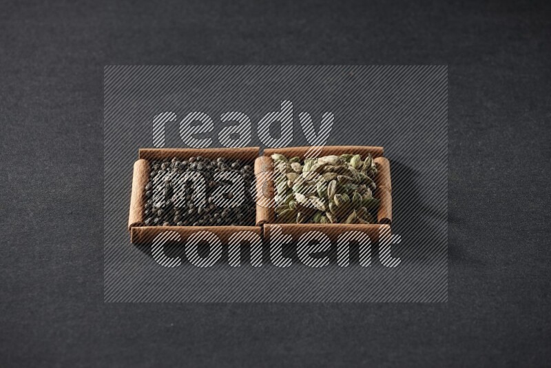 2 squares of cinnamon sticks full of black peppers and cardamom on black flooring