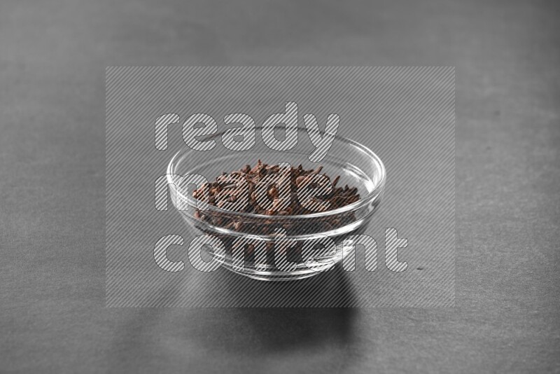 A glass bowl full of cloves on black flooring