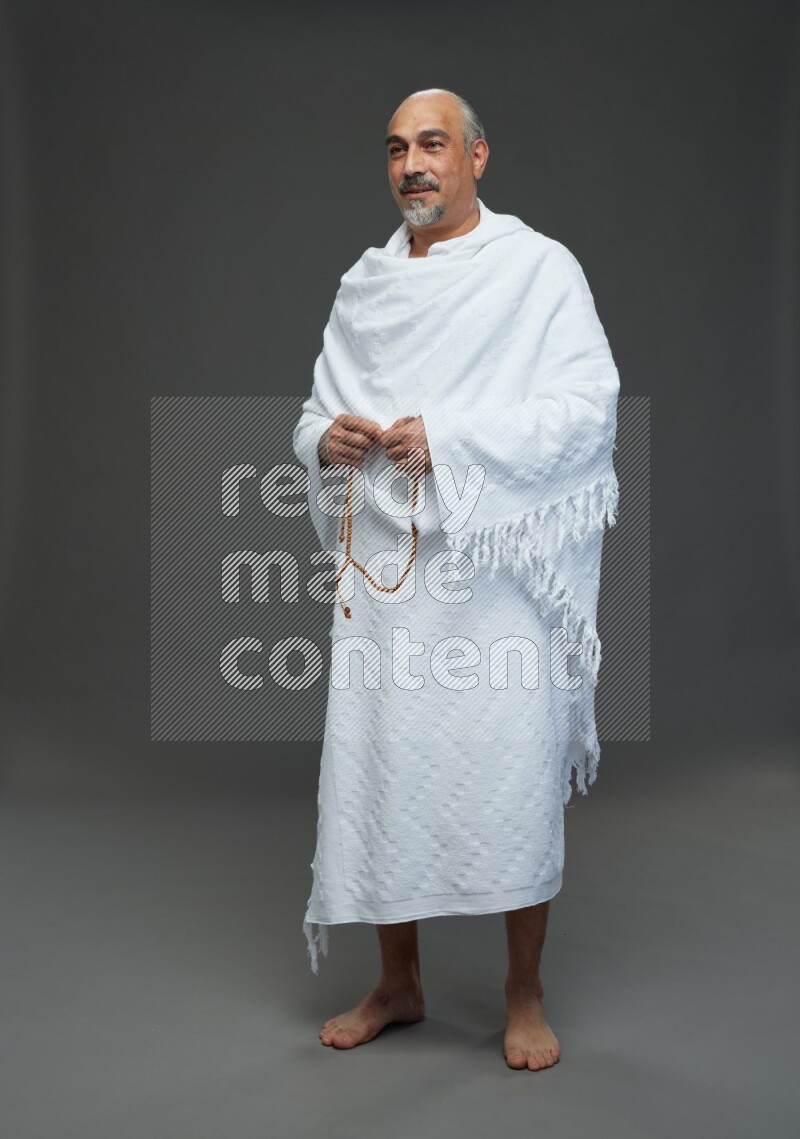A man wearing Ehram Standing holding rosary on gray background