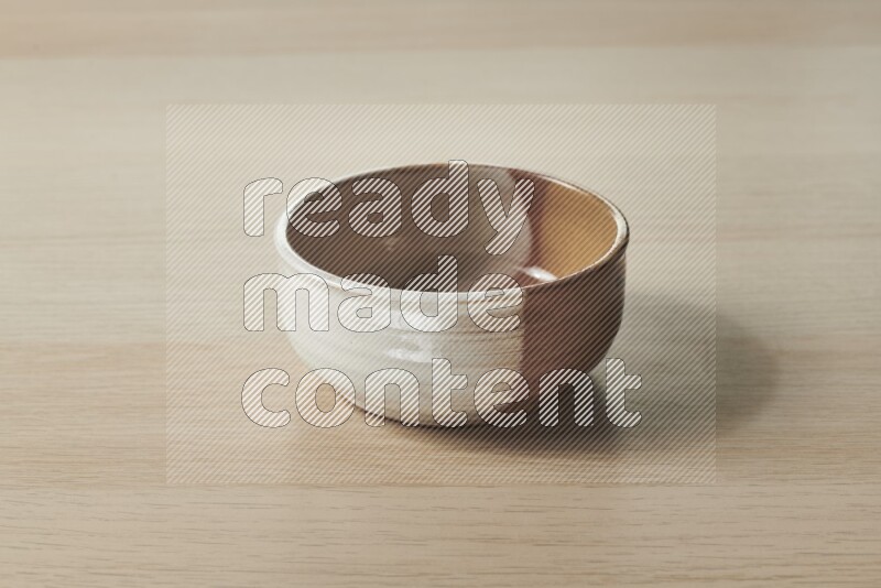 A multicolored pottery bowl on light wooden background