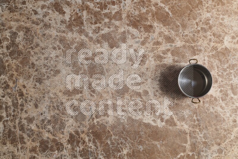 A small copper pot on beige marble background