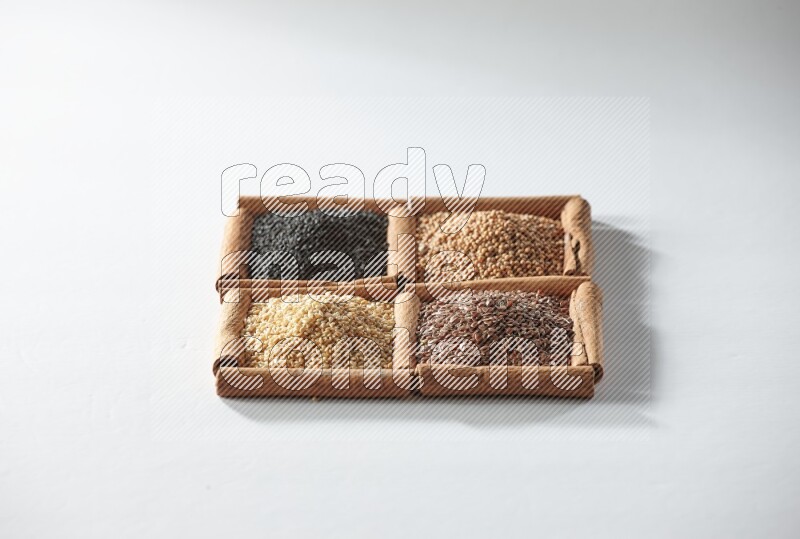 4 مربعات من أعواد القرفة ممتلئة بحبة البركة وبذور الخردل وبذور الكتان والسمسم على أرضية بيضاء