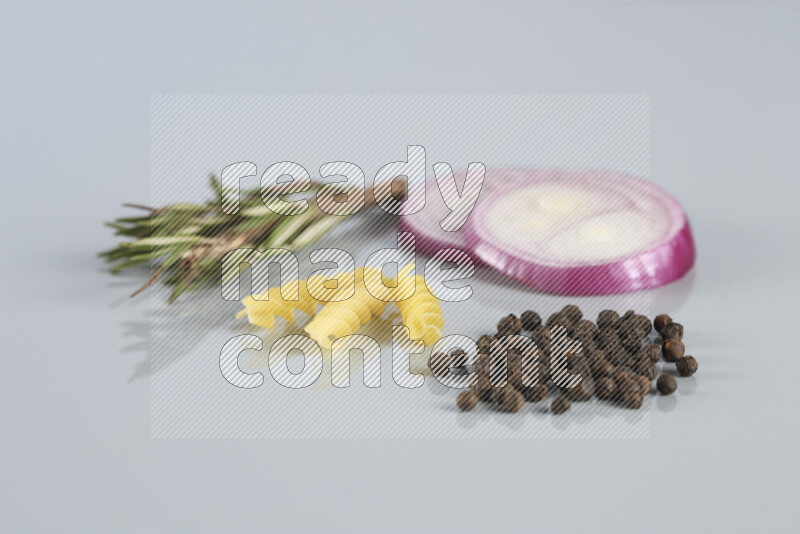Raw pasta with different ingredients such as cherry tomatoes, garlic, onions, red chilis, black pepper, white pepper, bay laurel leaves, rosemary, cardamom and mushrooms on light blue background