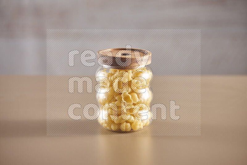 Raw pasta in glass jars on beige background