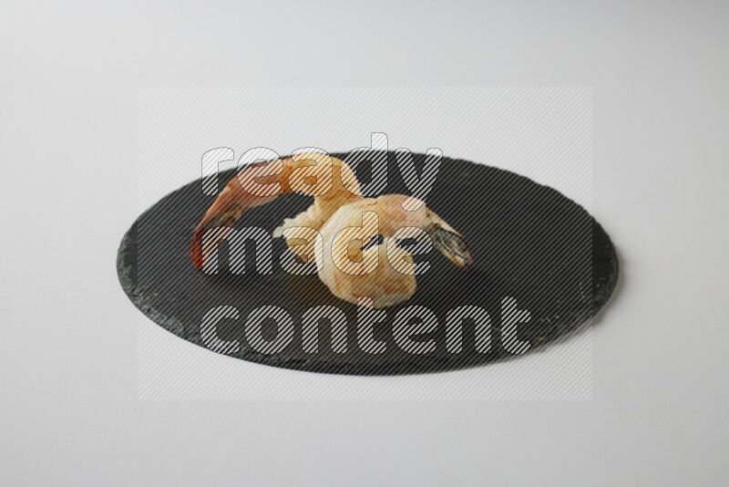 two grilled shrimp  on a black slate direct  on a white back ground
