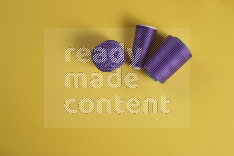 مجموعة من أدوات الخياطة والتفصيل إرجوانية اللون على خلفية صفراء