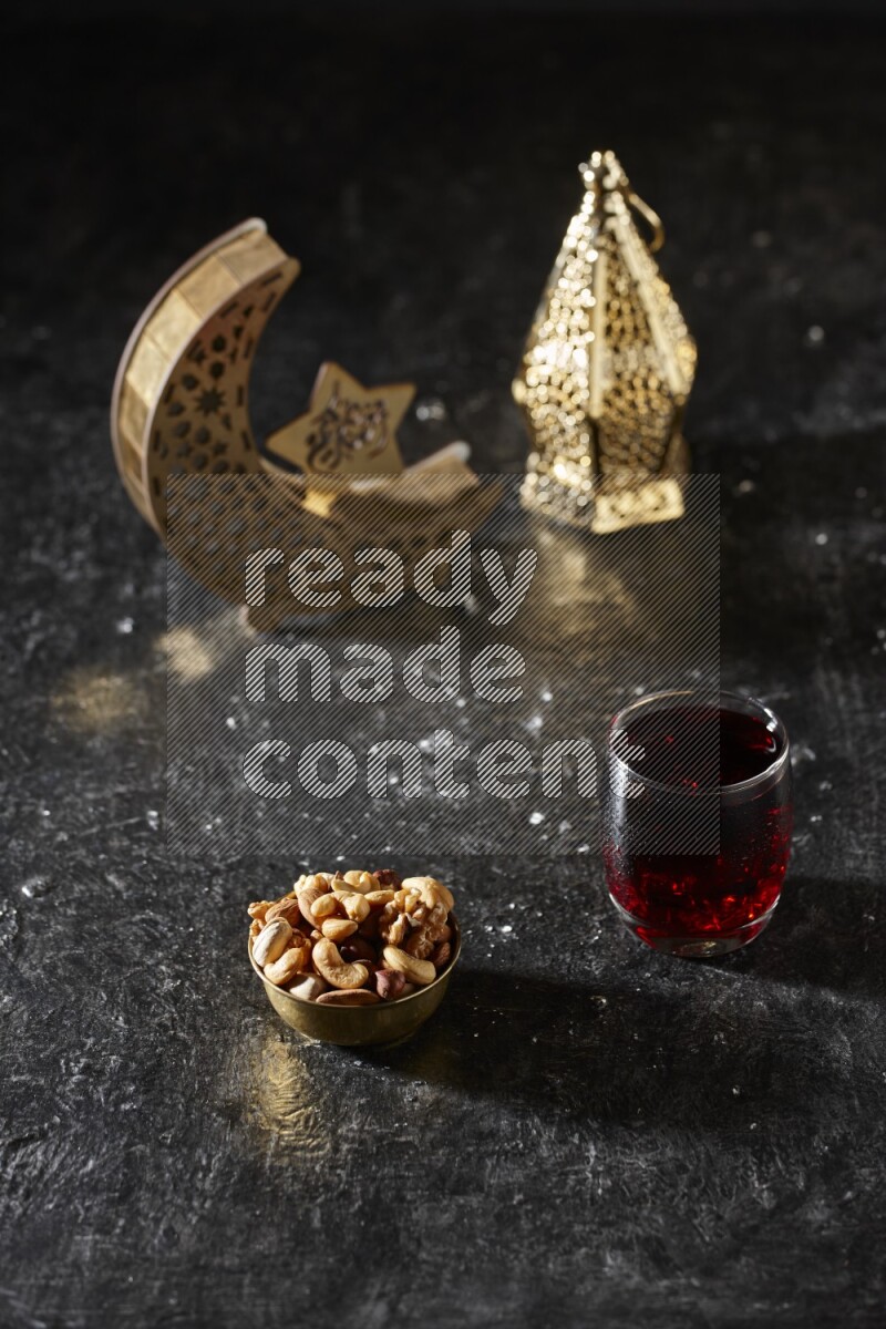 مكسرات في وعاء معدني مع مشروب الكركديه بجانب فوانيس ذهبية علي خلفية سوداء