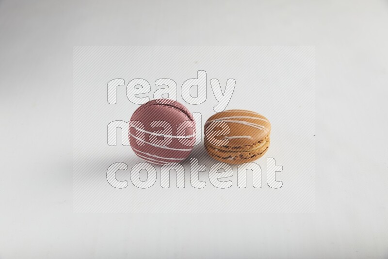 45º Shot of of two assorted Brown Irish Cream, and Red Poppy Flower macarons on white background