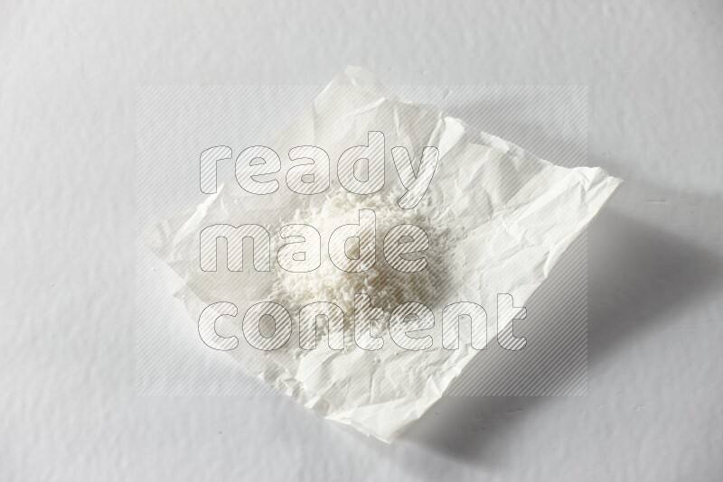 Desiccated coconut on a piece of paper on a white background in different angles