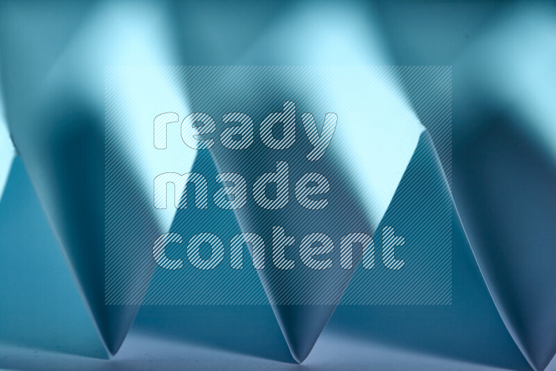 A close-up abstract image showing sharp geometric paper folds in blue gradients