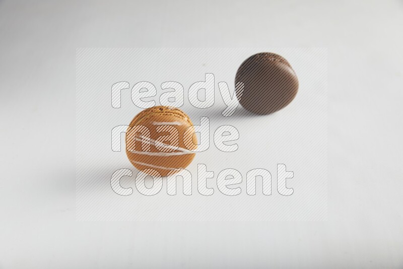45º Shot of of two assorted Brown Irish Cream, and Brown Dark Chocolate macarons on white background
