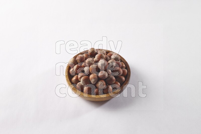Hazelnuts in a wooden bowl on white background