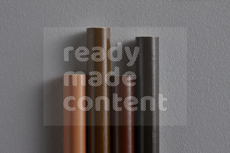 A collection of colored pencils arranged showcasing a gradient of brown hues on grey background