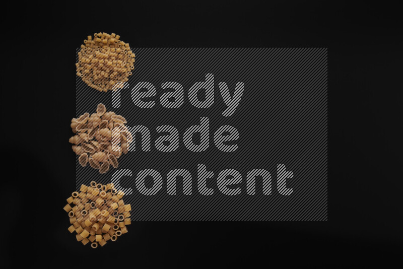 Different pasta types in 3 bunches on black background