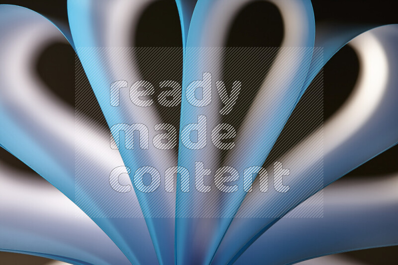 An abstract art piece displaying smooth curves in white and blue gradients created by colored light