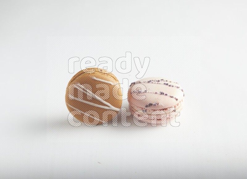 45º Shot of of two assorted Brown Irish Cream, and pink orange blossom macarons on white background