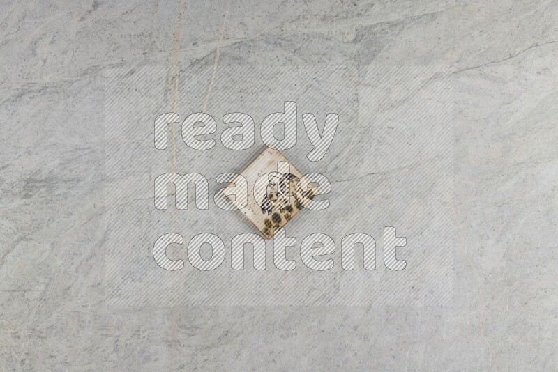 A decorative pottery coaster on grey marble background