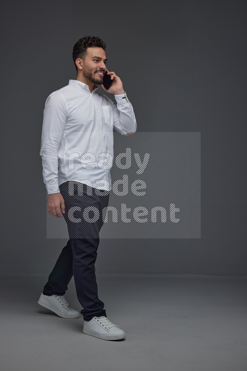 A man wearing smart casual talking in the phone eye level on a gray background