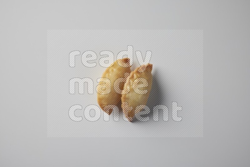 Two fried sambosa from a top angle on a white background